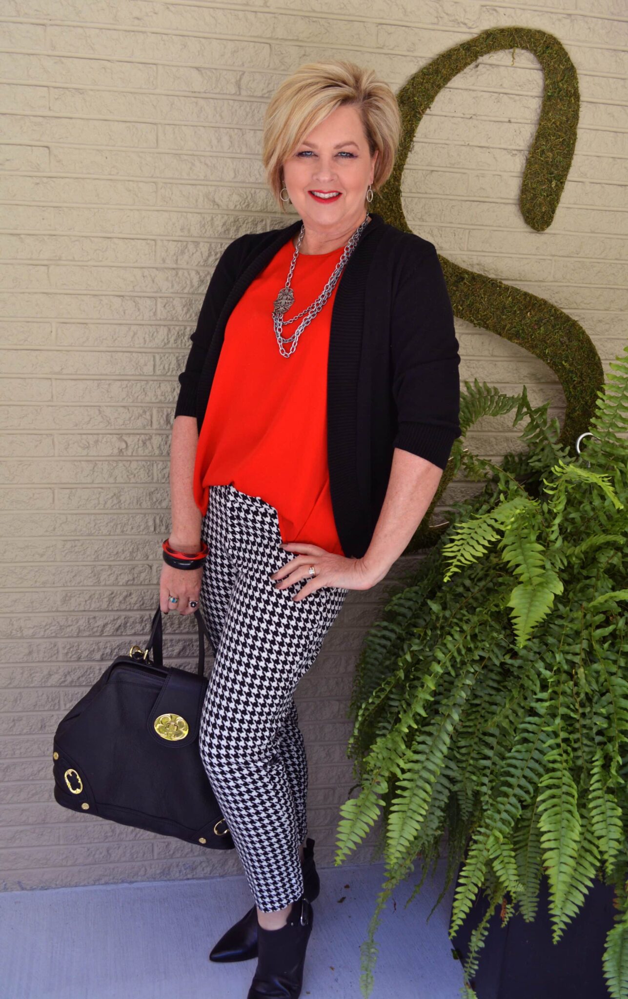 Tania wearing a red shirt with a black cardigan and houndstooth pants