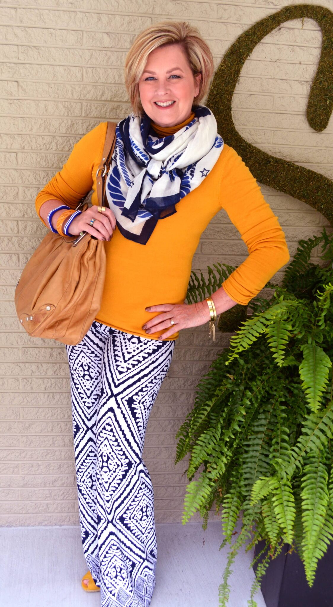 Tania wearing a bright yellow shirt with a blue and white scarf and pants