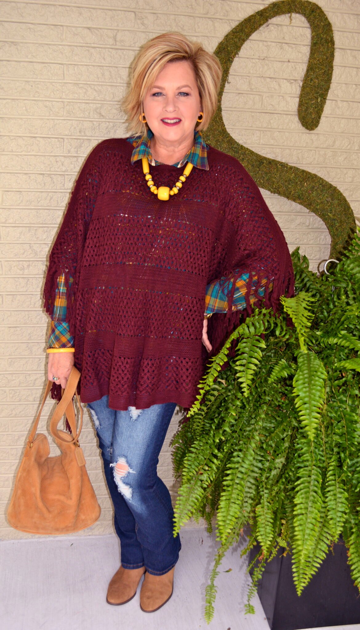Tania wearing a plaid shirt with a burgundy poncho with jeans