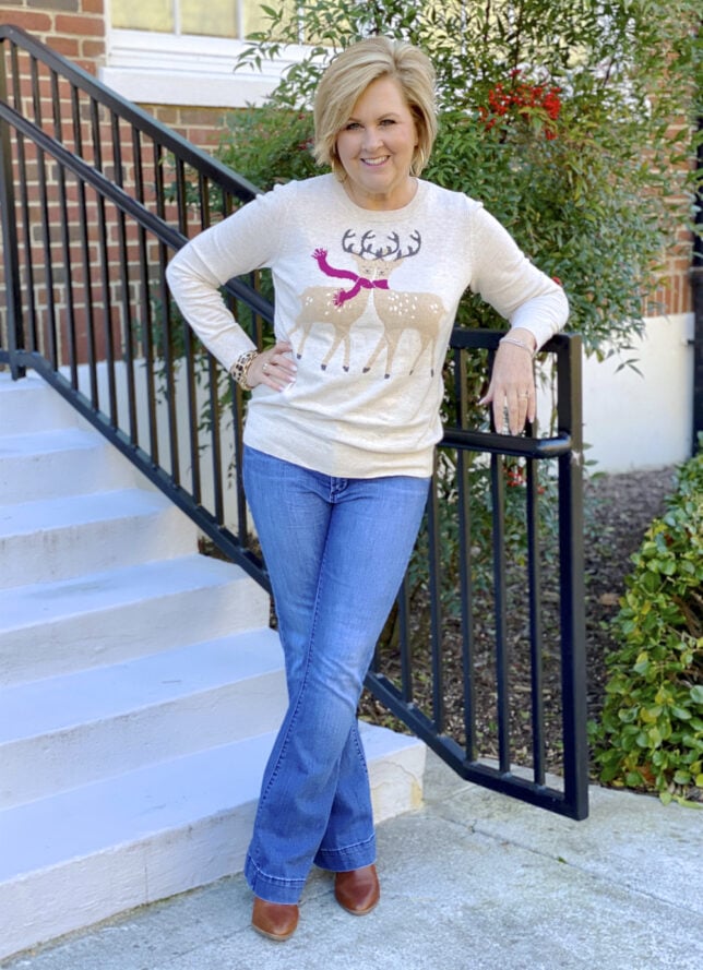 50 Is Not Old Fashion Blogger wearing a reindeer sweater with jeans and ankle boots