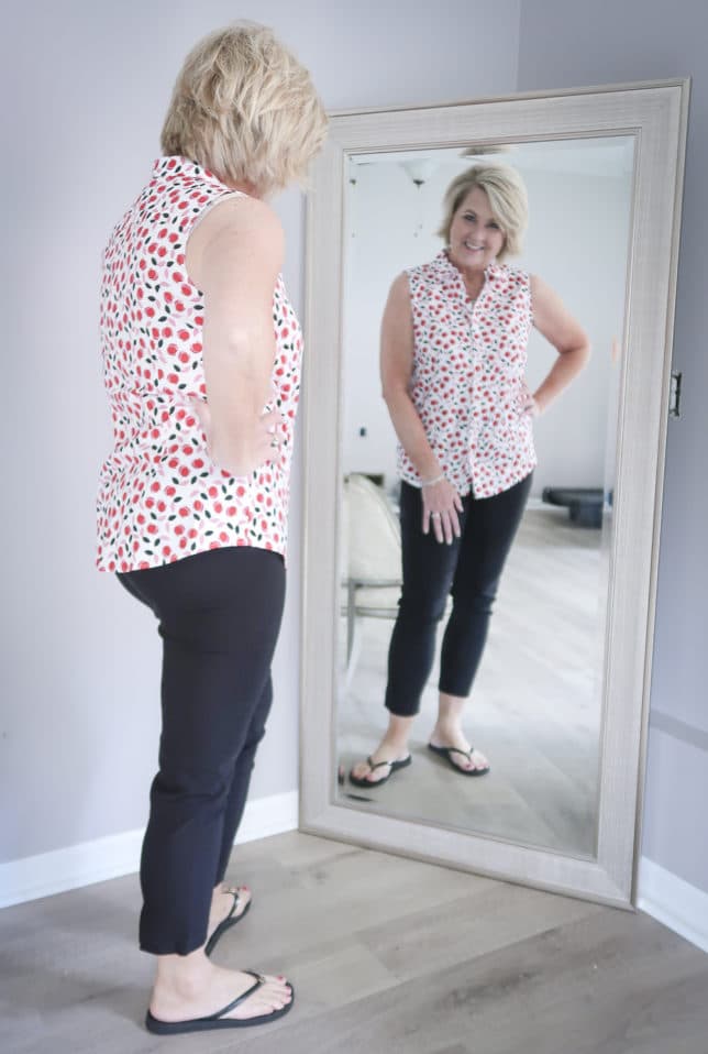 Fashion Blogger 50 Is Not Old is wearing a tulip print top with a pair of black crop pants and black Tory Burch flip flops