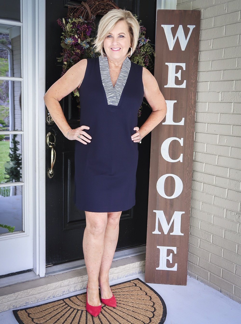 Fashion Blogger 50 Is Not Old is celebrating turning 60 with a navy sheath dress with a striped neckline and bright red pumps