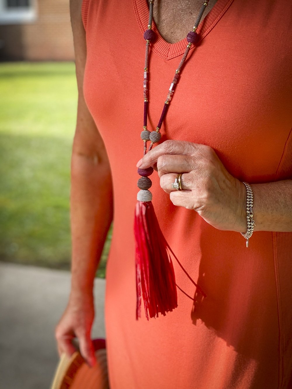 Fashion Blogger 50 Is Not Old is wearing an orange midi dress with a summerberry tassel necklace in pink all from Chico's