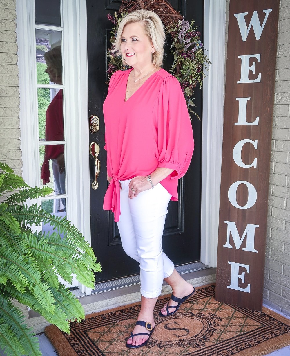 Fashion Blogger 50 Is Not Old is bright and colorful in a tie-front pink blouse and white girlfriend crop jeans