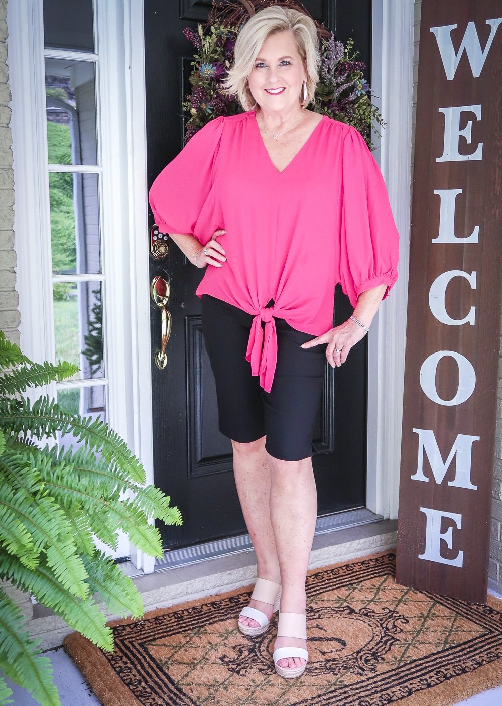 Fashion Blogger 50 Is Not Old is styling a beautiful pink front-tie blouse and black Bermuda shorts from Chicos