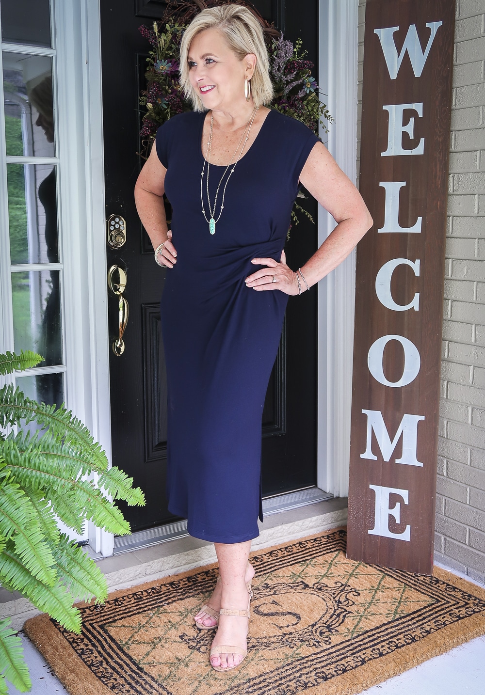 Fashion Blogger 50 Is Not Old is looking away and wearing a navy scoop neck midi dress with cork heels