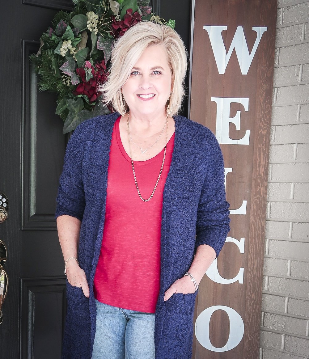 Fashion Blogger 50 Is Not Old is weekend ready in her burgundy t-shirt, distressed jeans, chunky knit cardigan, and wearing gold jewelry