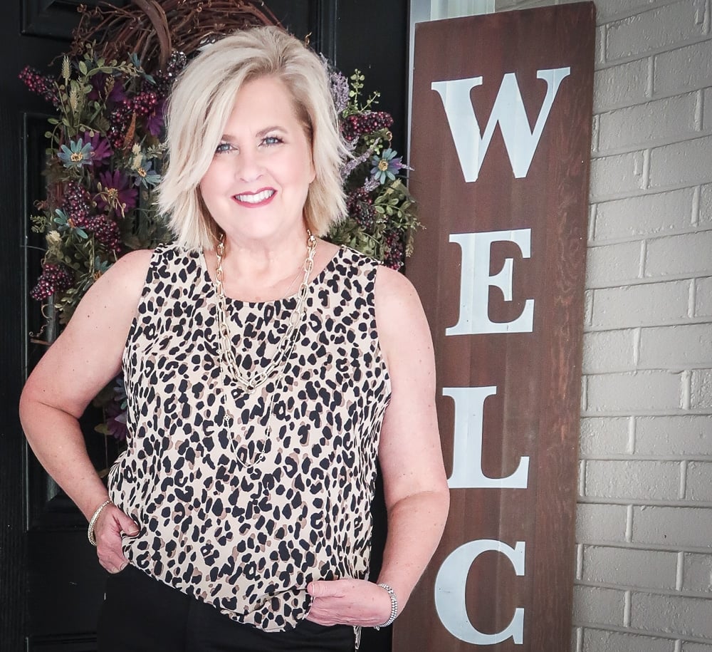 Fashion Blogger 50 Is Not Old is wearing a leopard print statement top and gold jewelry from Kendra Scott