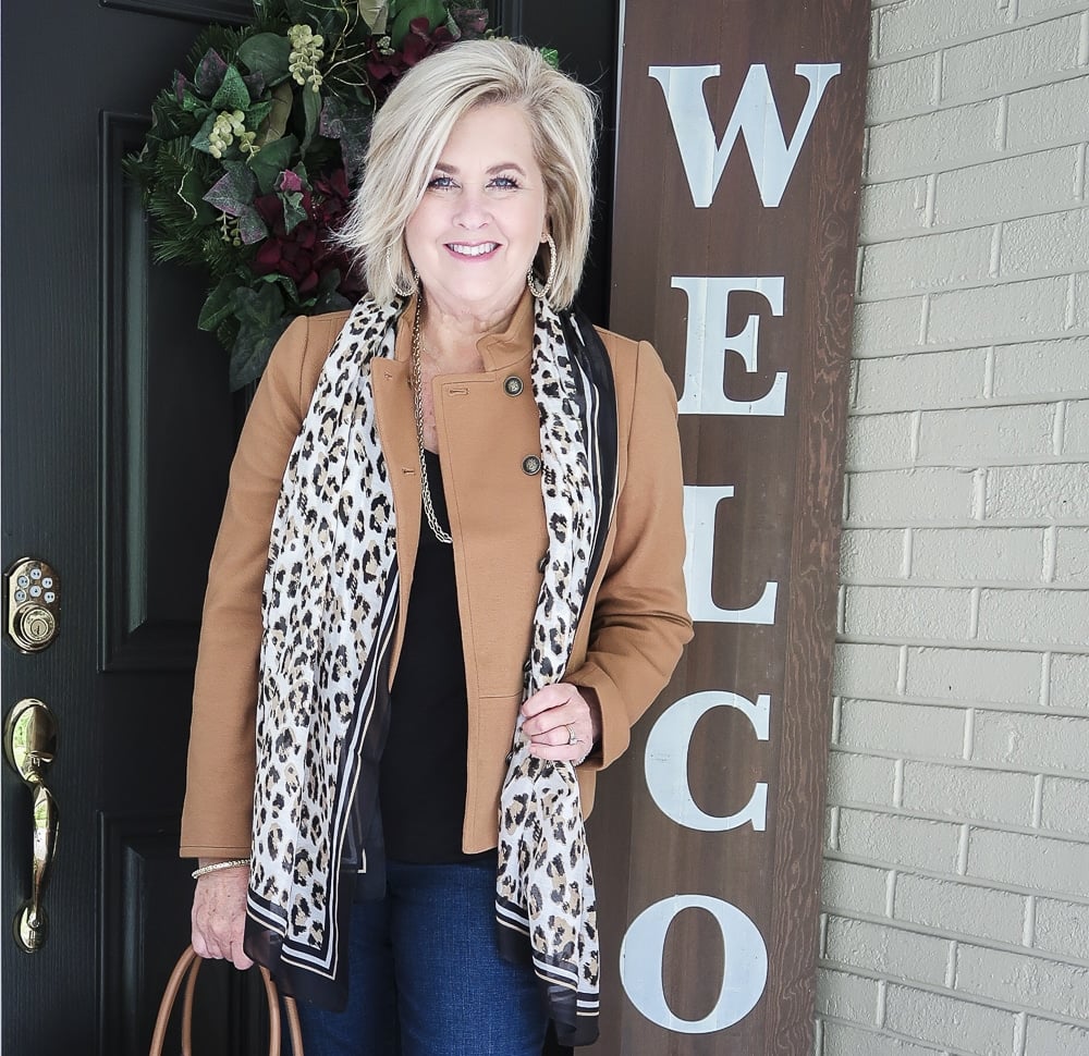 Fashion Blogger 50 Is Not Old is wearing a Camel jacket, a leopard print scarf, and a black v-neck top