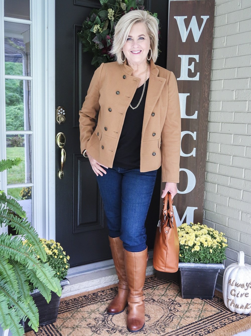 Fashion Blogger 50 Is Not Old is wearing a Camel jacket, a black v-neck top, straight leg jeans, brown knee boots from Naturalizer, and carrying a brown handbag
