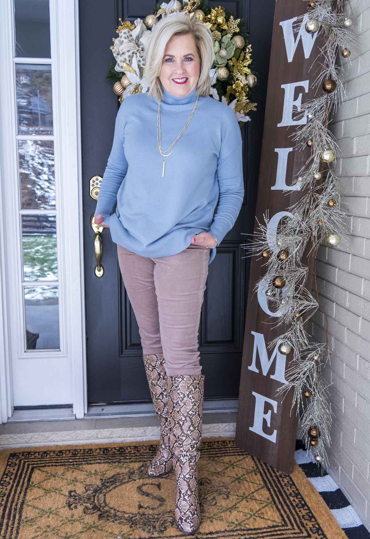 Fashion Blogger 50 Is Not Old is wearing a blue turtleneck sweater with a pair of taupe corduroy pants from Loft. A pair of snake skin knee boots from Target finished the look.