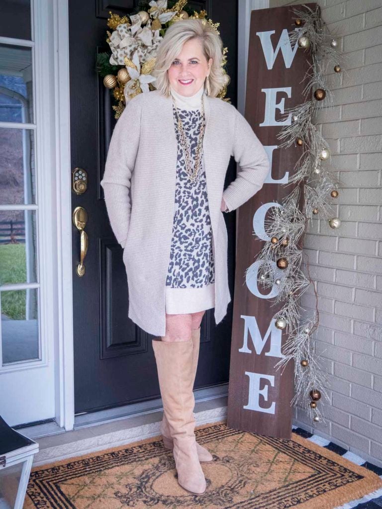 Fashion Blogger 50 Is Not Old is wearing a leopard print turtleneck sweater dress, a oatmeal colored cardigan, and a pair of suede tall boots