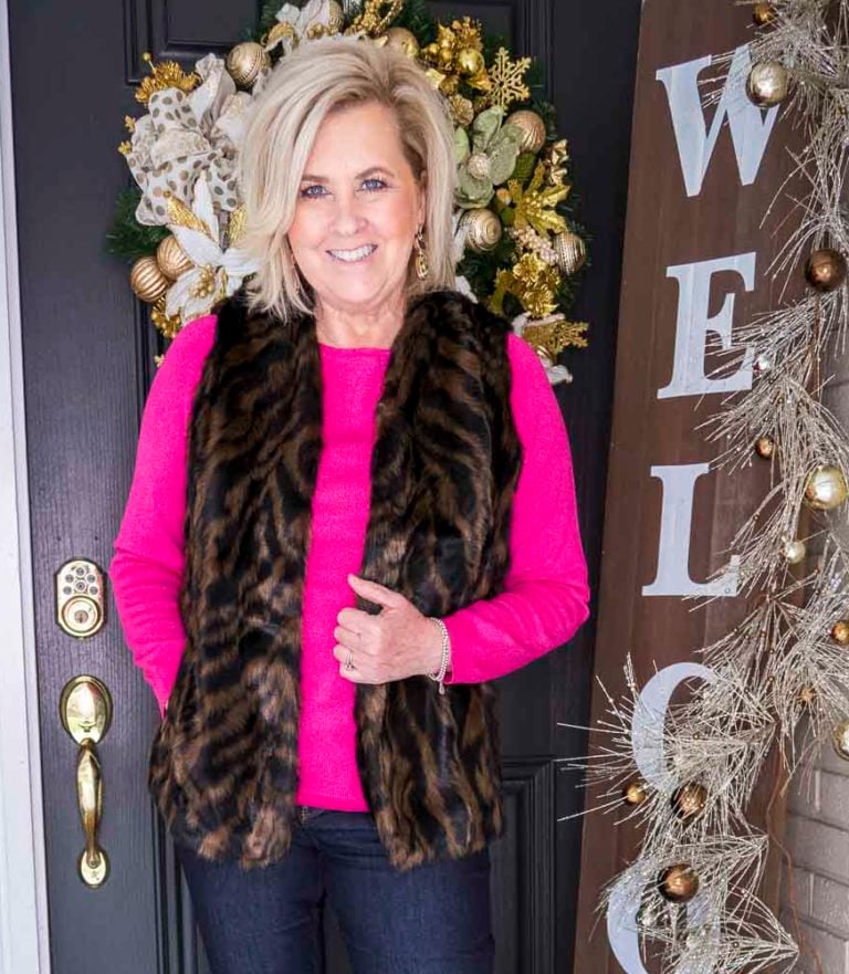 Over 40 Fashion Blogger 50 Is Not Old is wearing a bright pink sweater with a tiger print faux fur vest