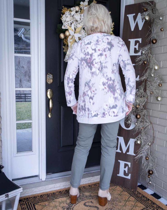Fashion Blogger 50 Is Not Old is showing the back of a sweatshirt tunic top with a pair of cargo pants and neutral colored ankle boots