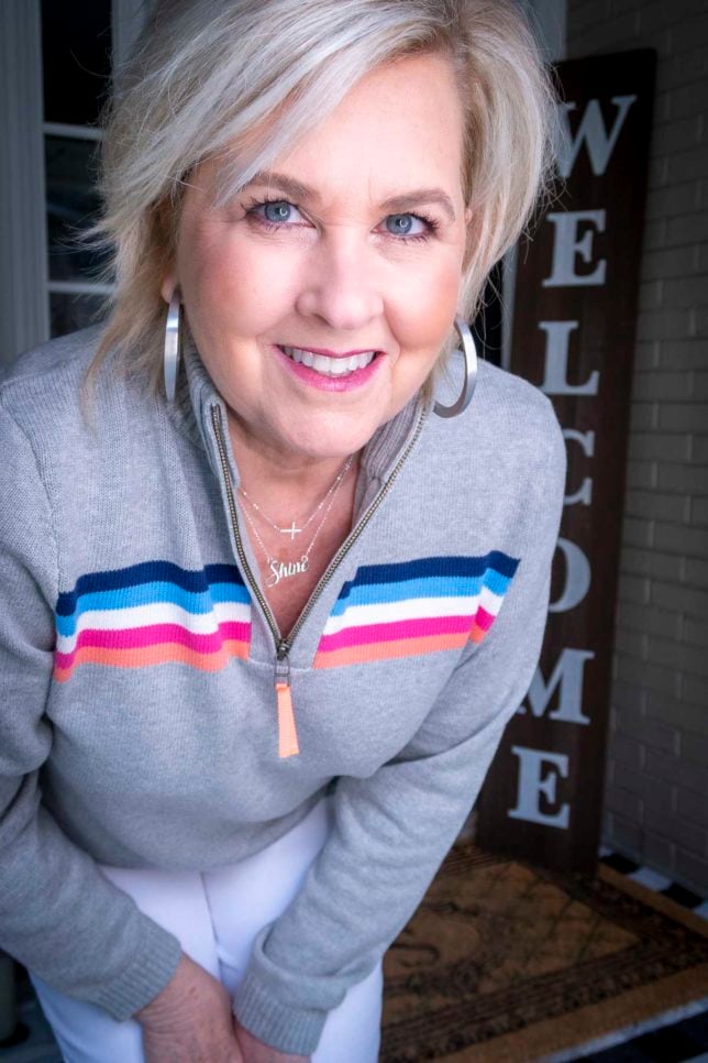 Fashion Blogger 50 Is Not Old is wearing a rainbow striped pullover sweater and silver hoop earrings
