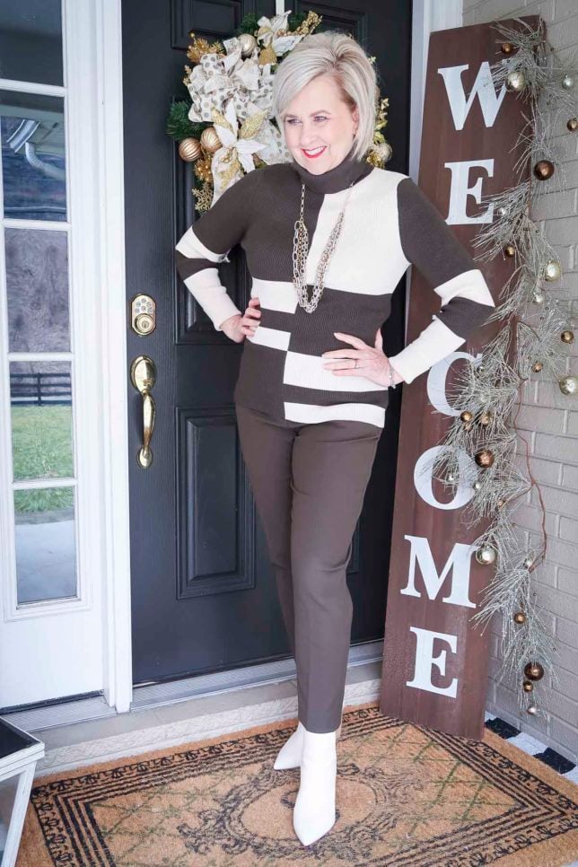 Fashion Blogger 50 Is Not Old is wearing a colorblocked turtleneck with ankle pants and white ankle boots