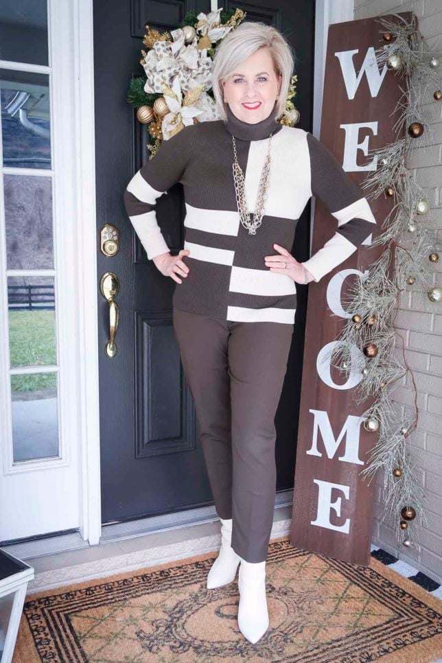 Fashion Blogger 50 Is Not Old is wearing a patterned turtleneck with ankle pants, and white ankle boots