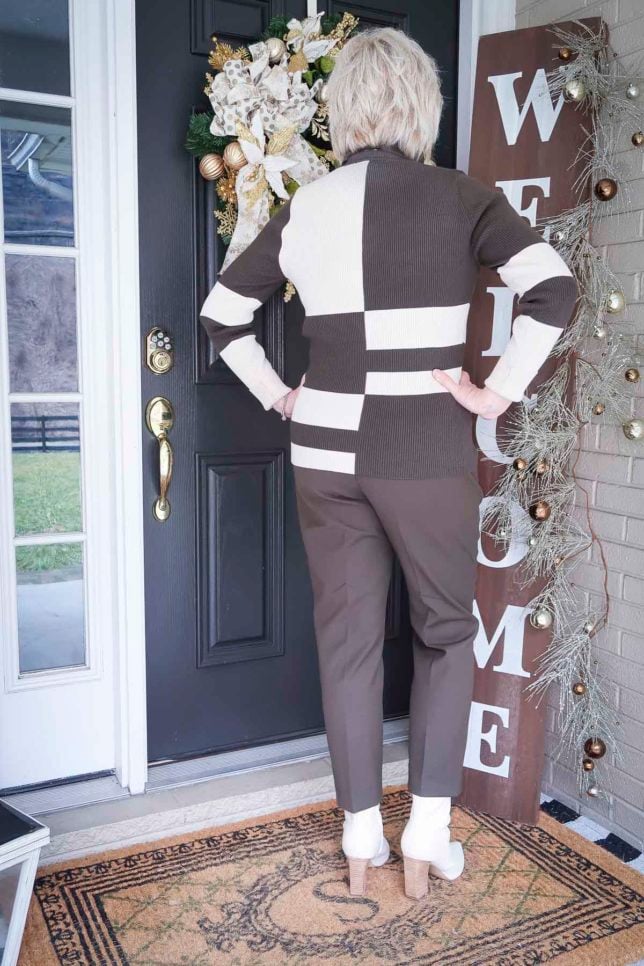 Fashion Blogger 50 Is Not Old is showing the back of a colorblocked turtleneck with ankle pants and white ankle boots