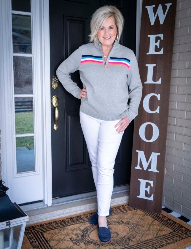 Fashion Blogger 50 Is Not Old is wearing a rainbow striped sweater and white ankle jeans with navy loafers