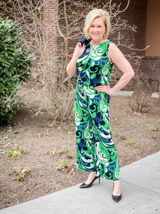Fashion Blogger 50 Is Not Old is wearing a green and blue printed jumpsuit with black pumps