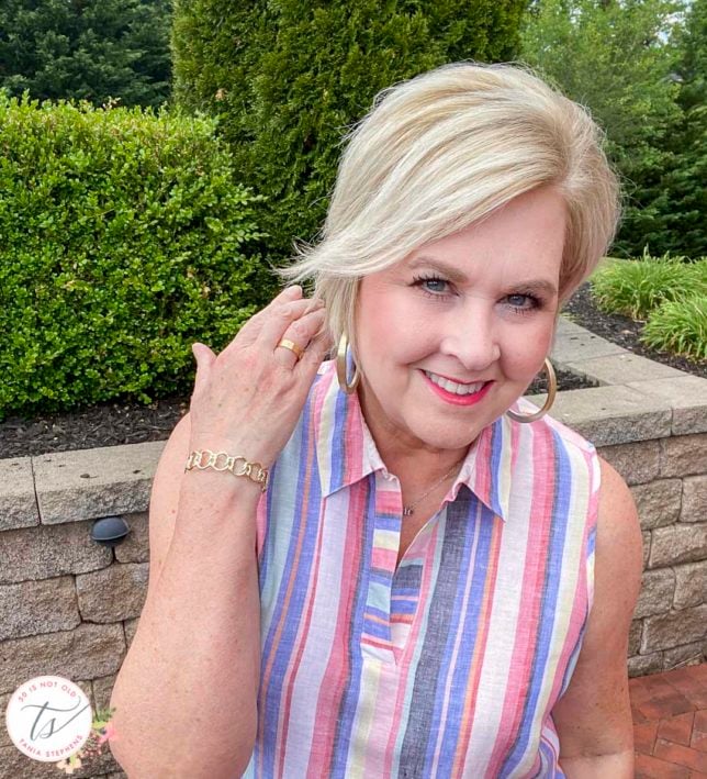 Fashion Blogger 50 Is Not Old is wearing a linen striped tunic top and gold jewelry from Kendra Scott