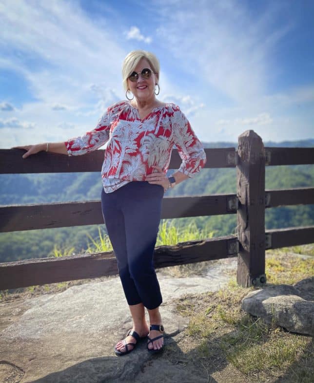 Fashion Blogger 50 Is Not Old went sightseeing in an orange gauze blouse, navy crop pants, and navy sandals with a wooden buckle