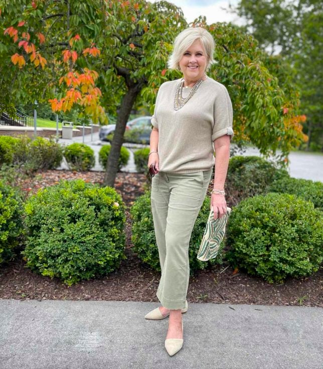 Fashion Blogger 50 Is Not Old is showing an example of wearing neutrals for the fall with a embellished sweater, olive crop pants, and neutral flats
