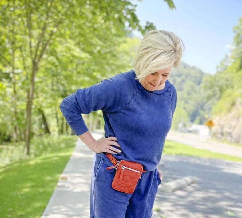 Over 40 Fashion Blogger, Tania Stephens, is wearing a navy sweatshirt and a crossbody Terracotta bag from Vera Bradley