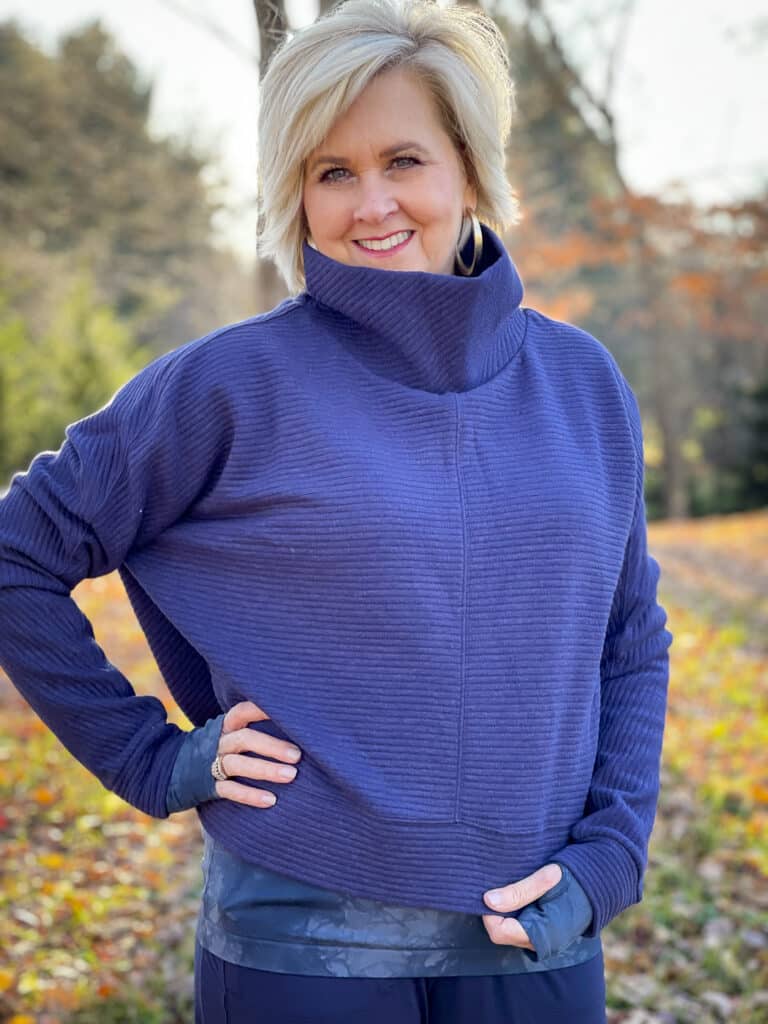Over 40 Fashion Blogger, Tania Stephens is out for a walk in the woods in a funnel neck Zella pullover