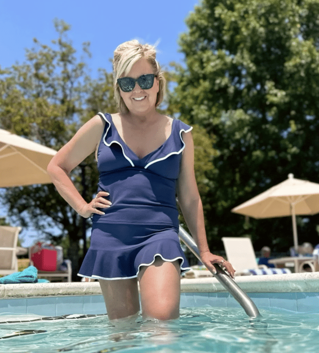 Tania standing in a pool in a navy & white tankini