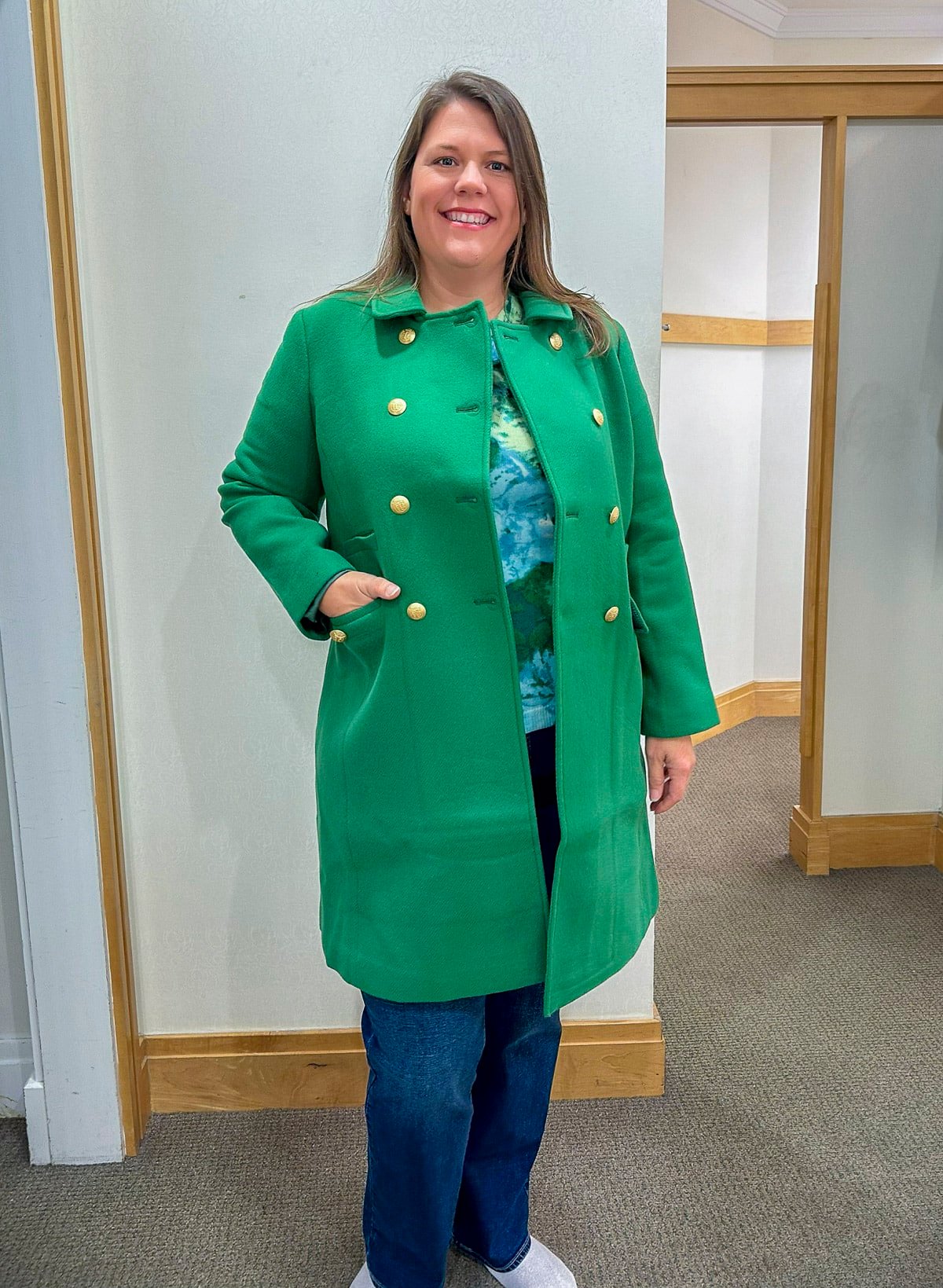 Megan is trying on a Talbots green coat, a floral sweater and bootcut jeans