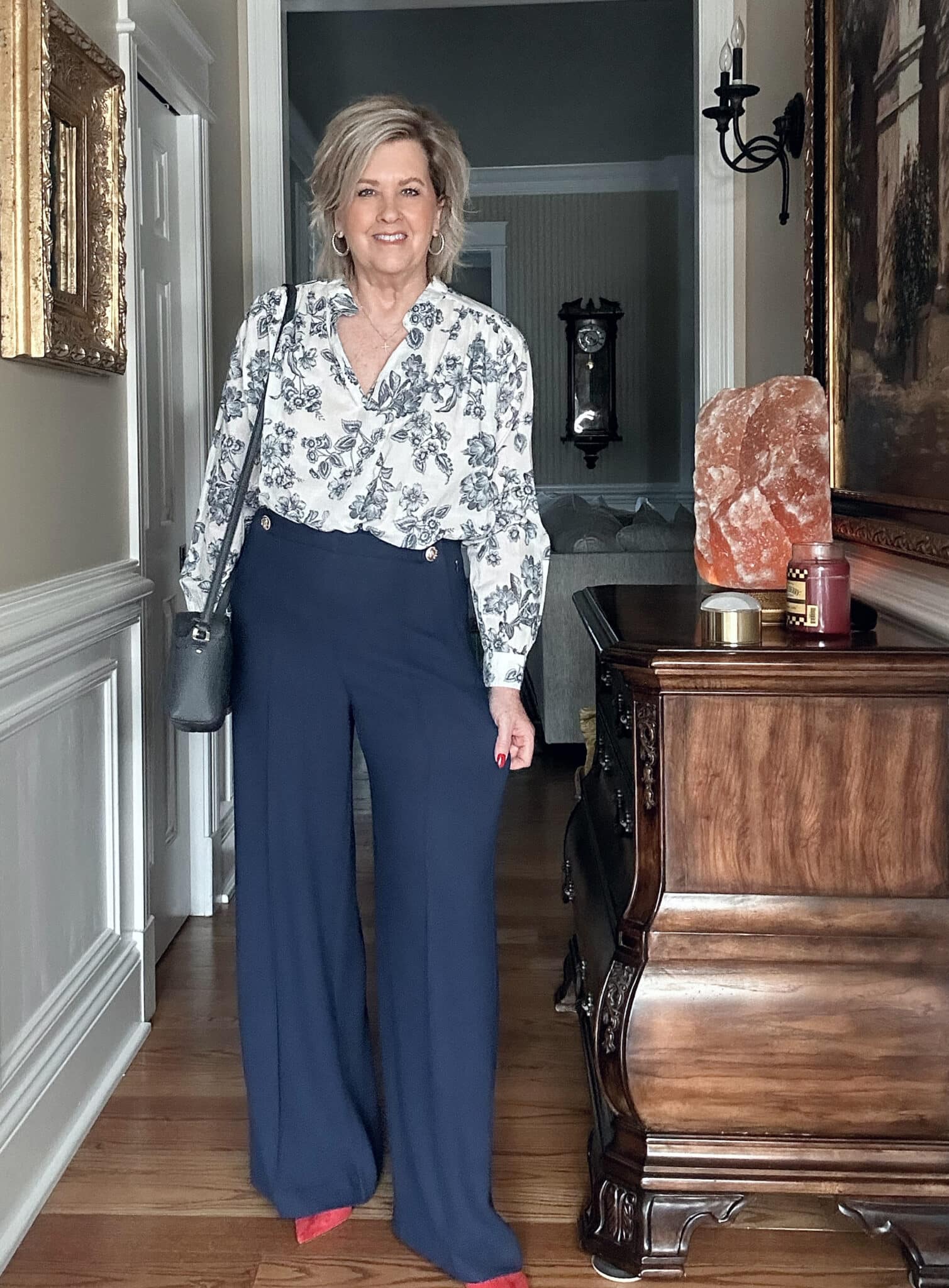 Over 50 fashion blogger, Tania Stephens is wearing a blue floral top and navy wide leg pants 