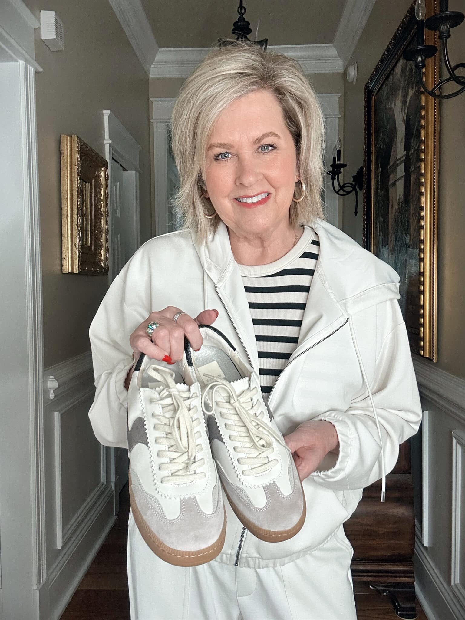 Over 50 Fashion Blogger, Tania Stephens is wearing a neutral outfit consisting of an ivory zip hoodie and a pair of Dolce Vita sneakers