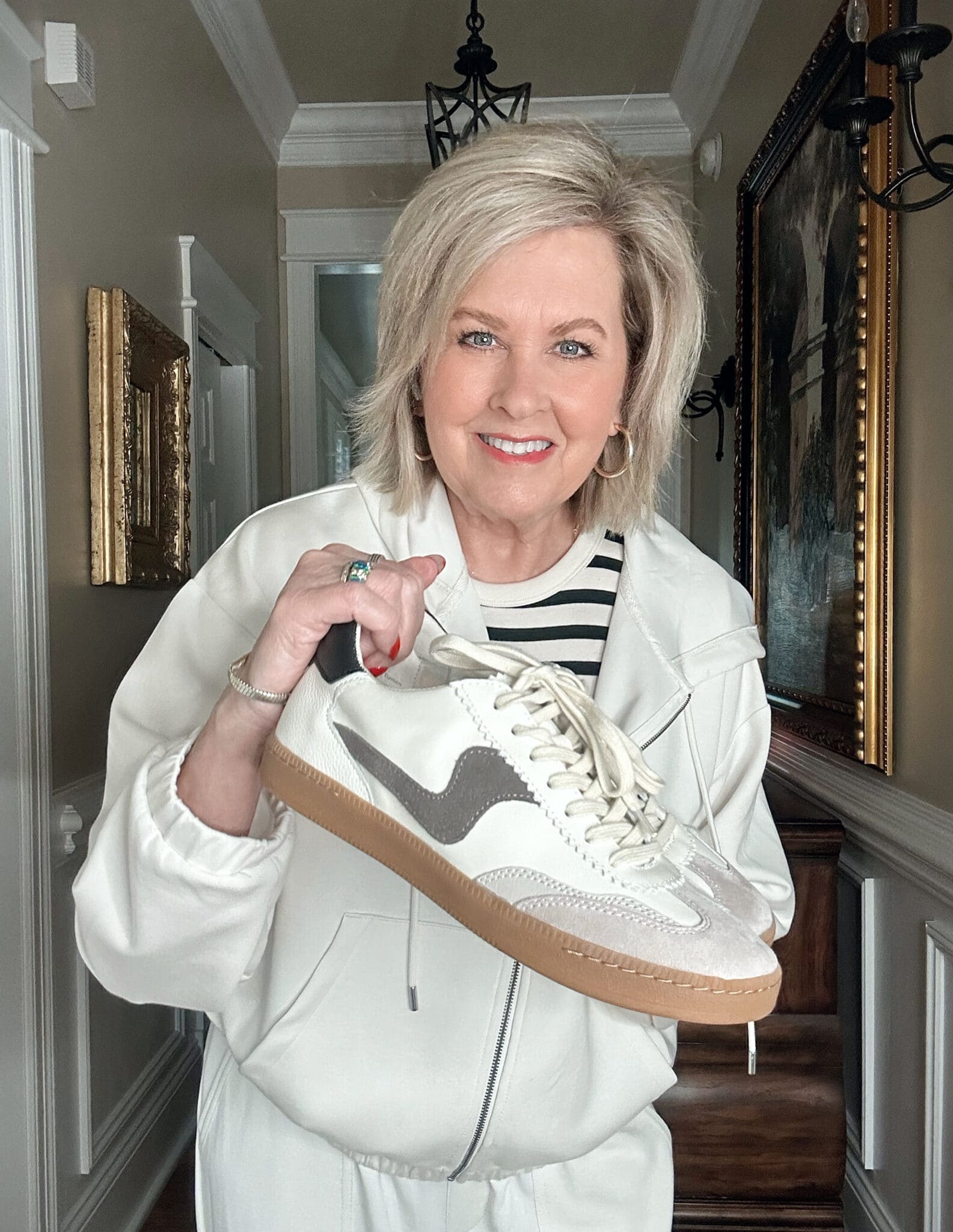 Over 50 Fashion Blogger, Tania Stephens is wearing a neutral outfit consisting of an ivory zip hoodie and a pair of sneakers by Dolce Vita 