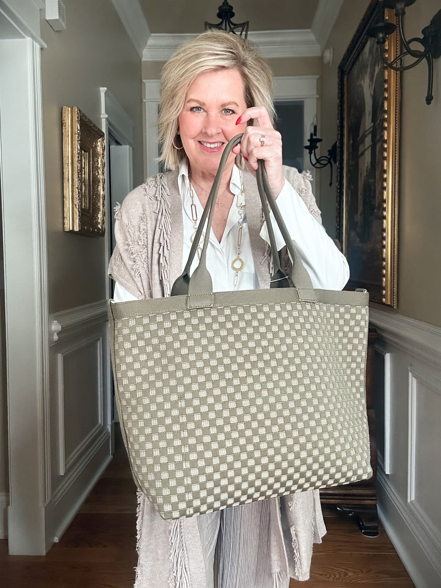 Over 50 Fashion Blogger, Tania Stephens is wearing a neutral outfit consisting of a fringed vest with a Rothy's handbag