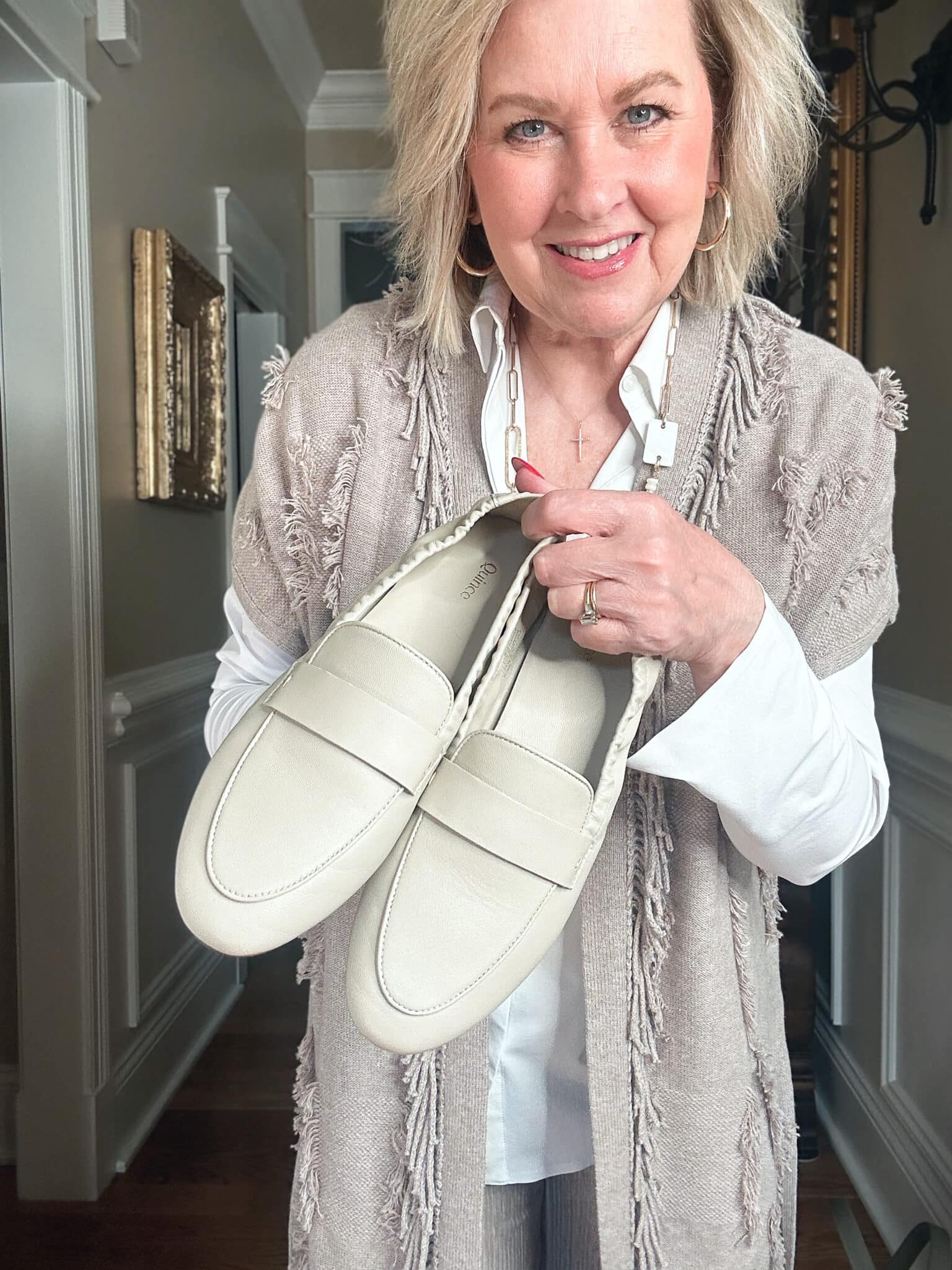 Over 50 Fashion Blogger, Tania Stephens is wearing a neutral outfit consisting of a fringed vest with beige loafers from Quince