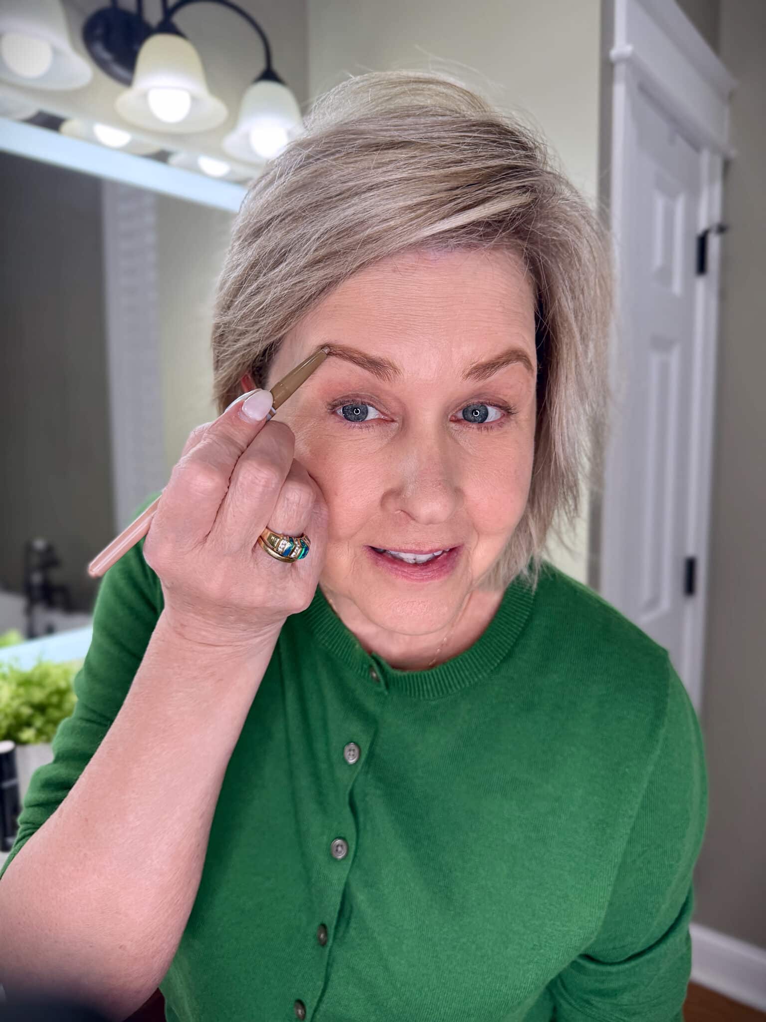 Tania Stephens in a green sweater with outlining eyebrows with makeup from Nordstrom Beauty