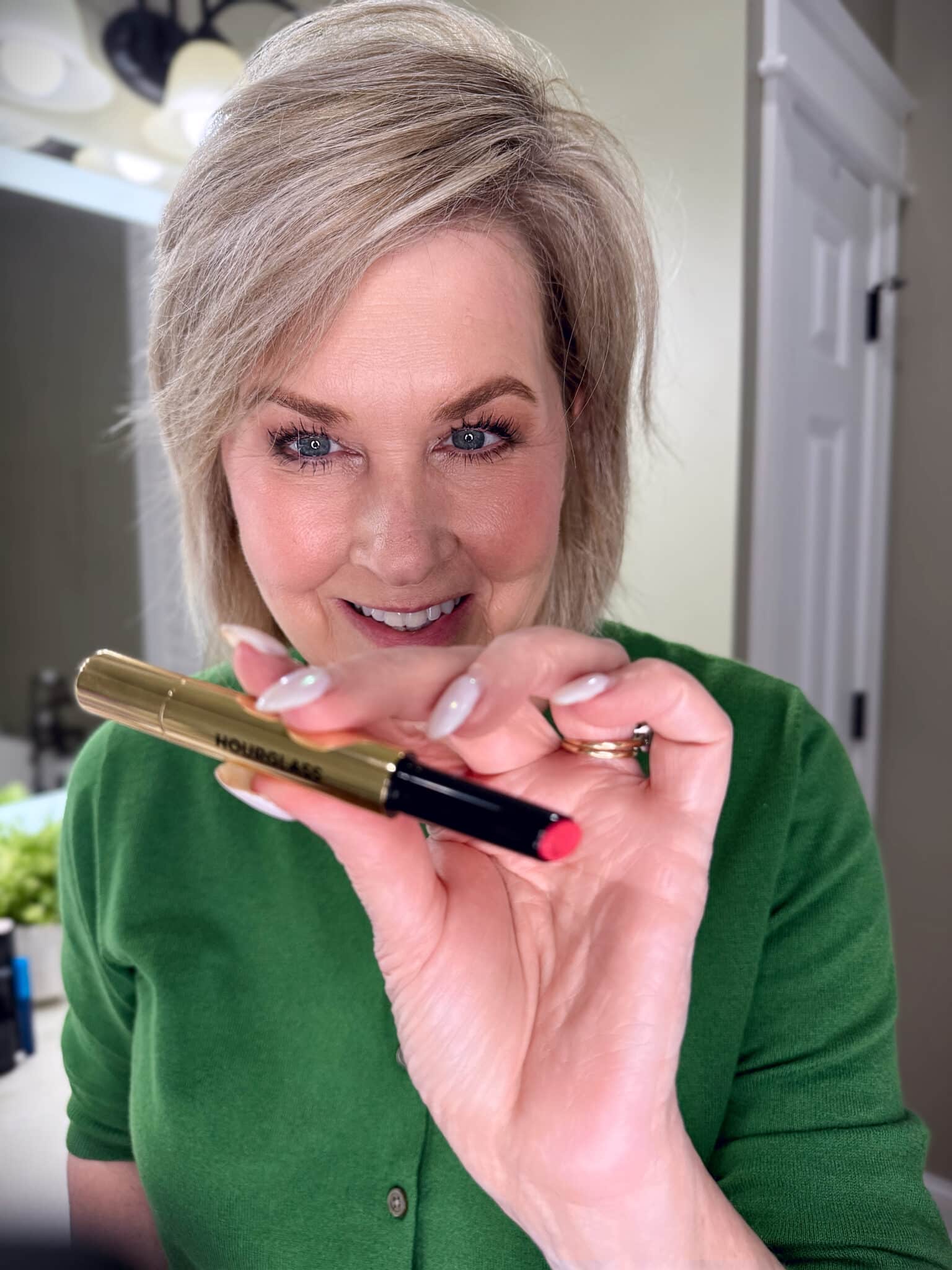 Tania Stephens in a green sweater with Hourglass lip balm makeup from Nordstrom Beauty