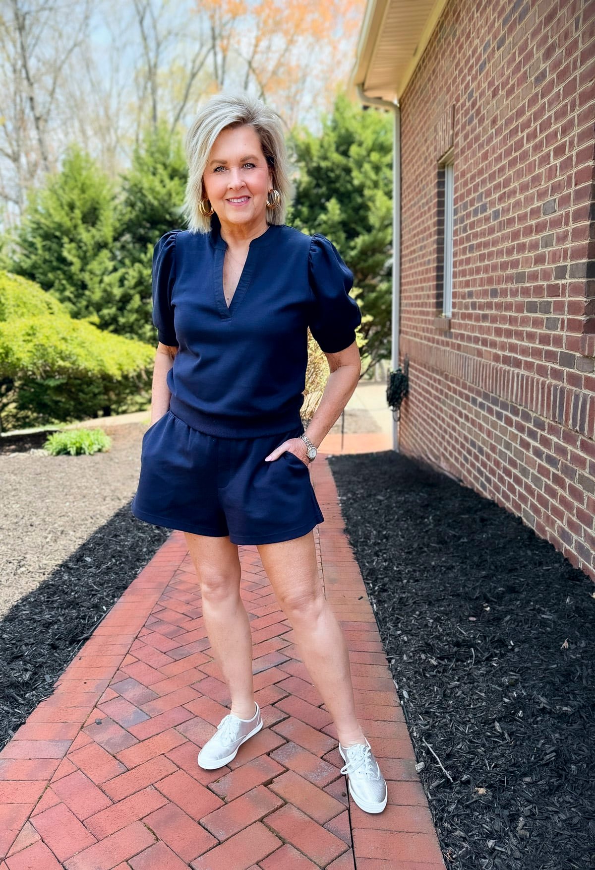 Woman in a navy short set and Champion Leather Luxe Lace Up sneakers