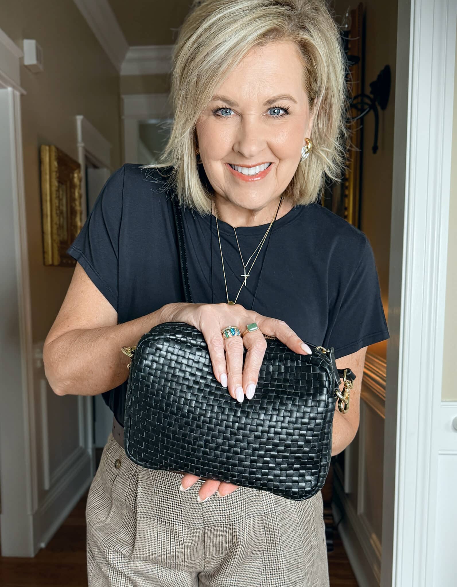 woman wearing a linen blazer with a black top with a woven handbag
