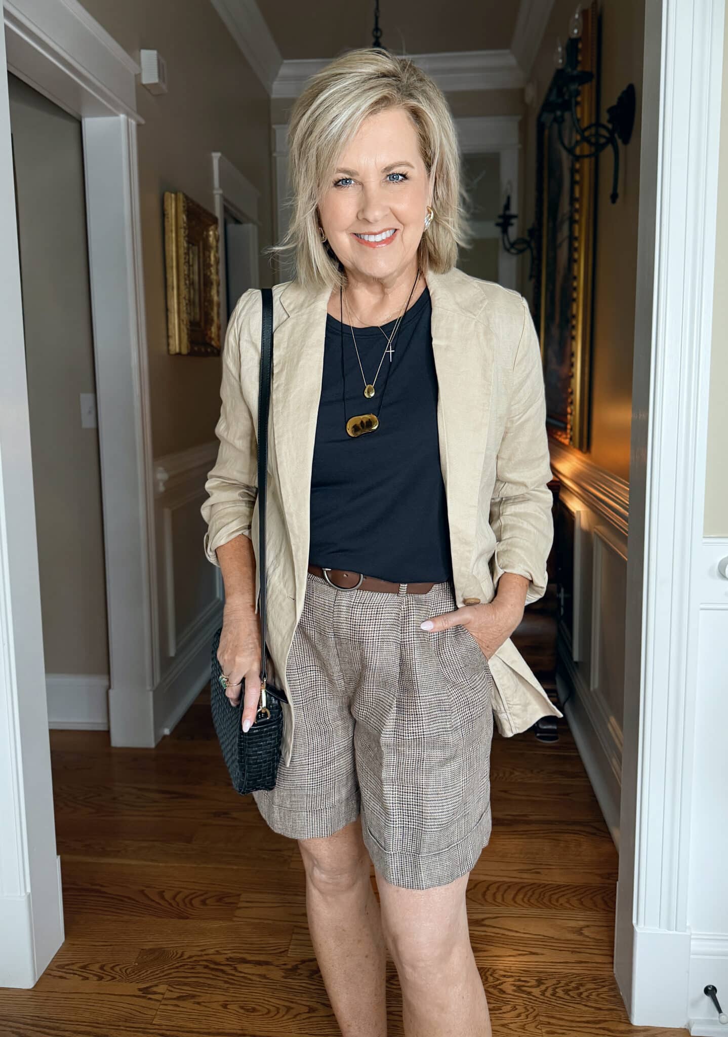 woman wearing a linen blazer with a black top with plaid Bermuda shorts