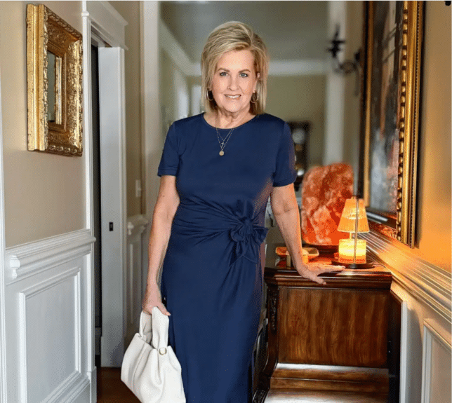 Tania wearing a navy tie waist dress with a white handbag