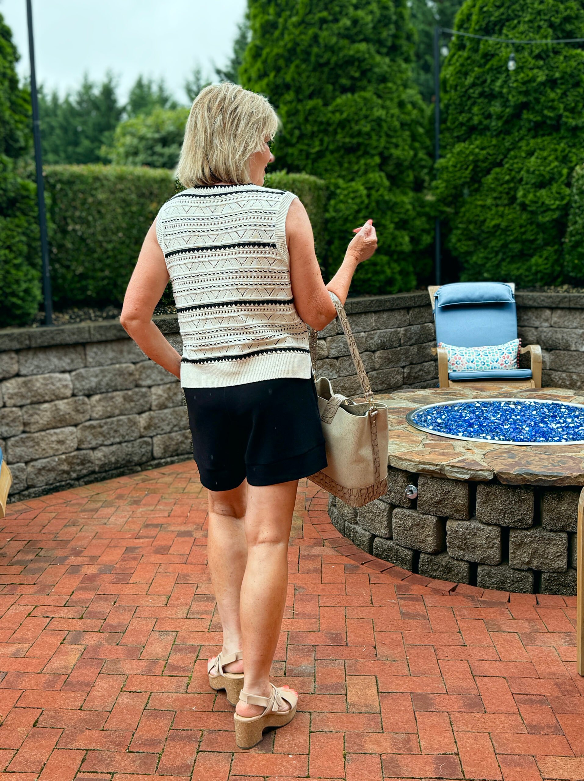 Tania showing the back of a crochet top in black and ivory and black shorts from Varley