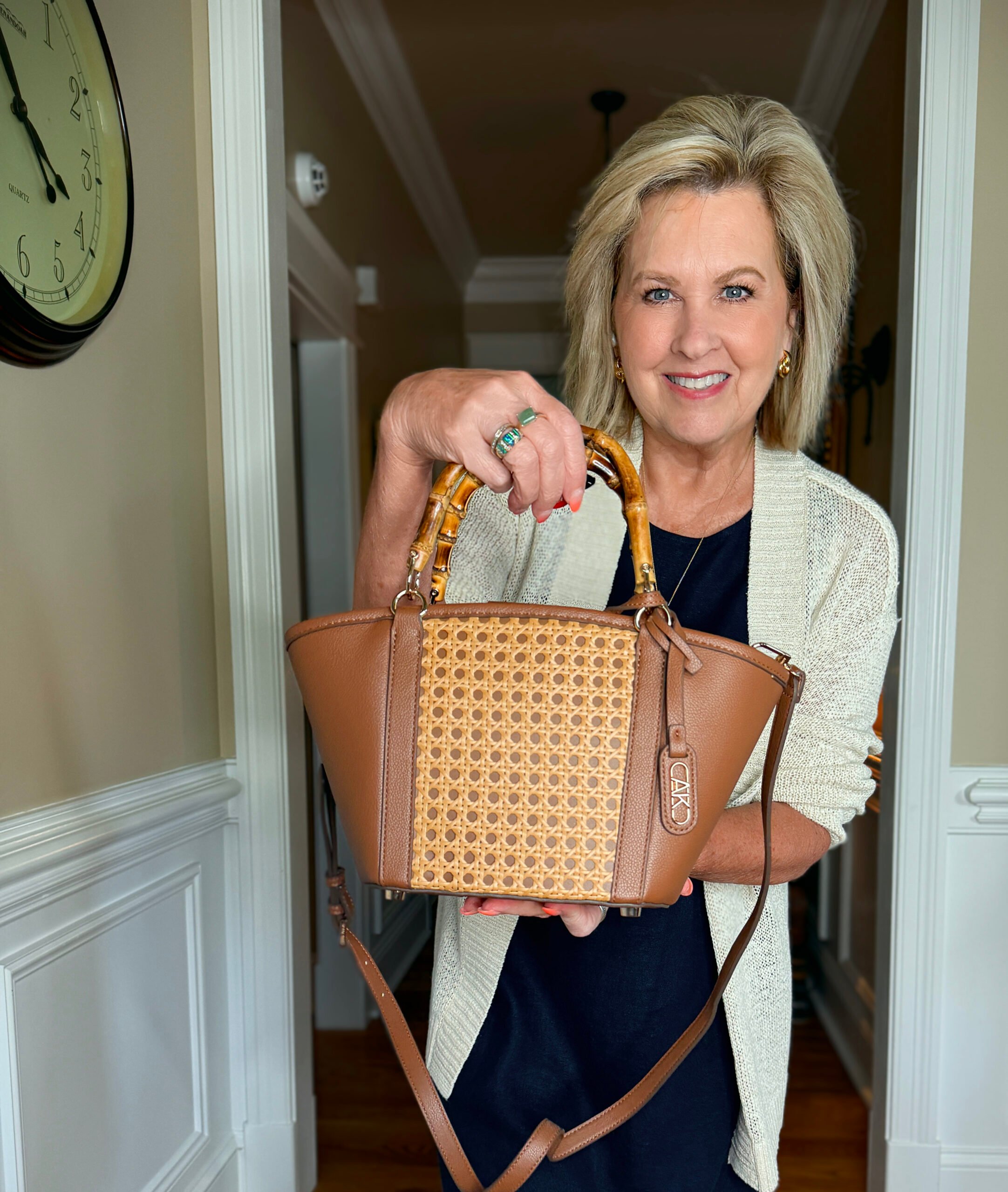 Tania wearing a navy dress and holding a rattan satchel