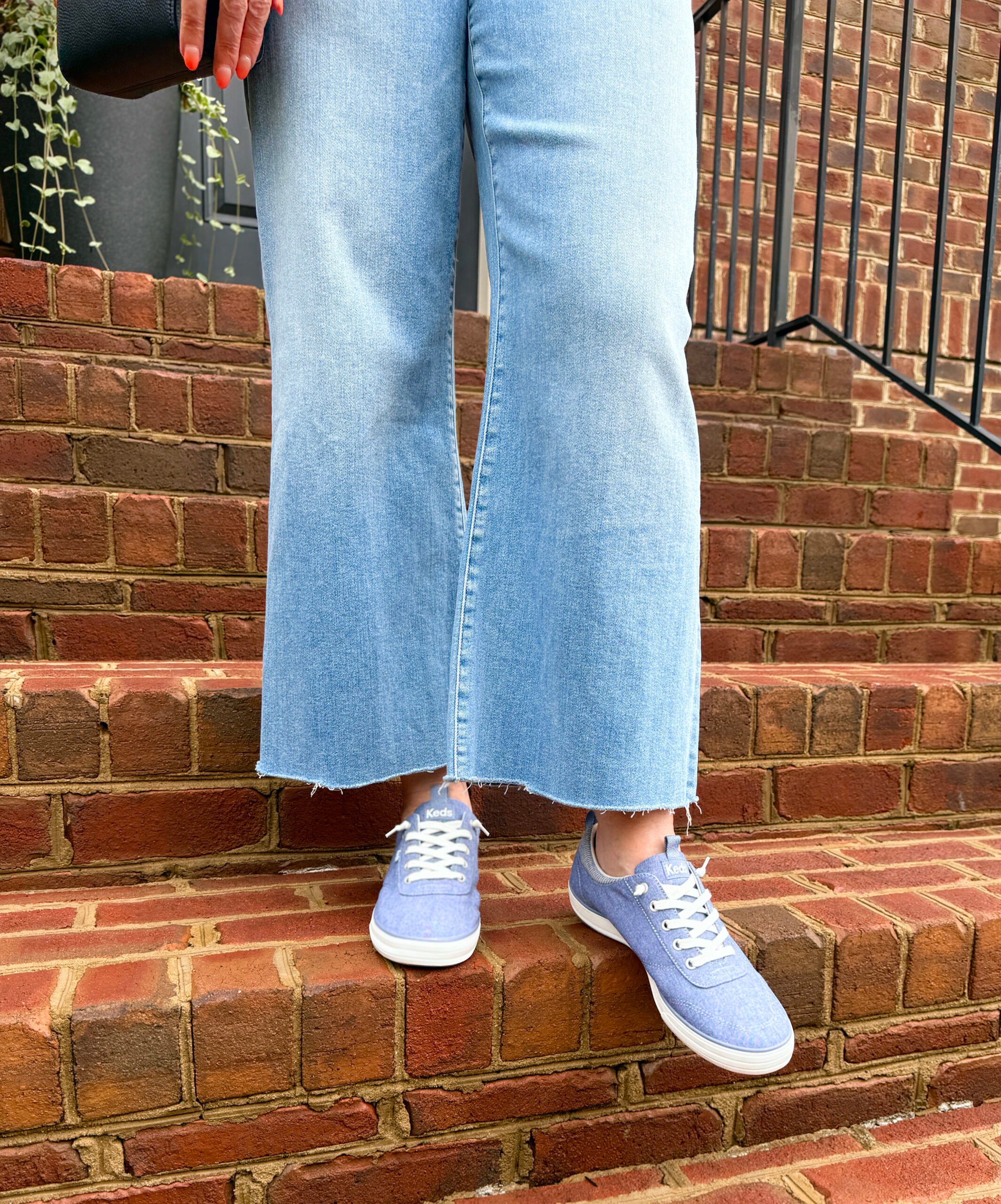 woman walking down brick steps im jeans and Keds Center III Chambray Slip-On Sneakers