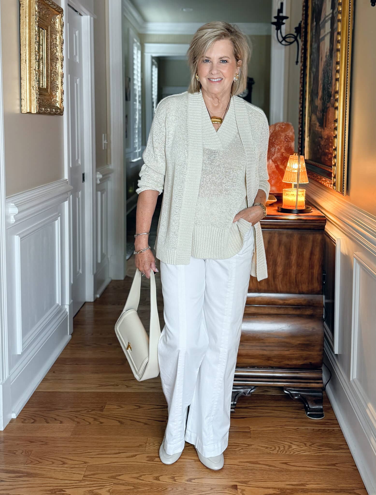 Tania wearing soft Italian loafers with white wide-leg jeans and a layered organic cotton sweater vest and cardigan for a cozy neutral look