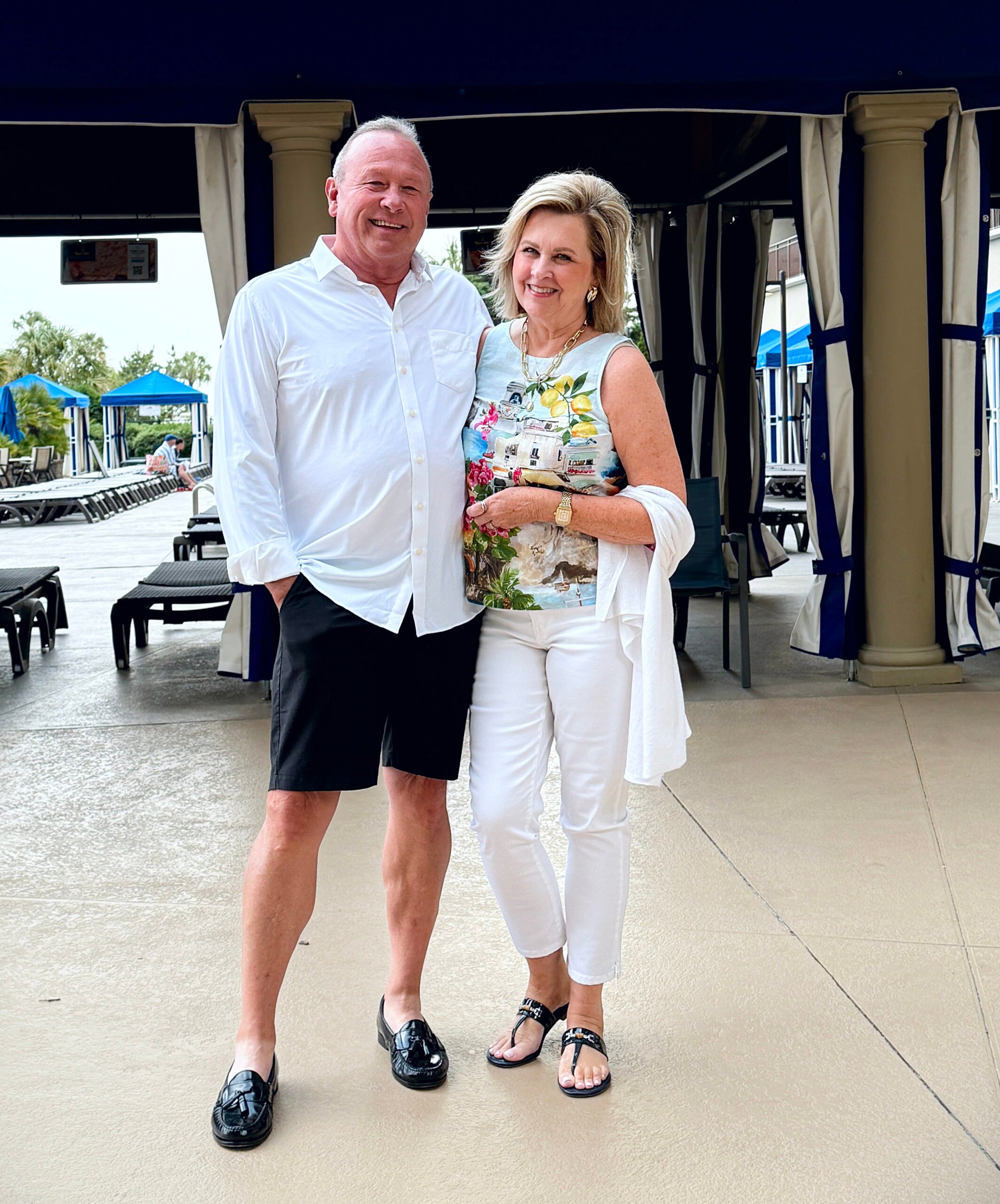 Tania wearing bamboo thong sandals with white jeans, linen shell top, and a light ruana wrap, styled for a summer vacation look
