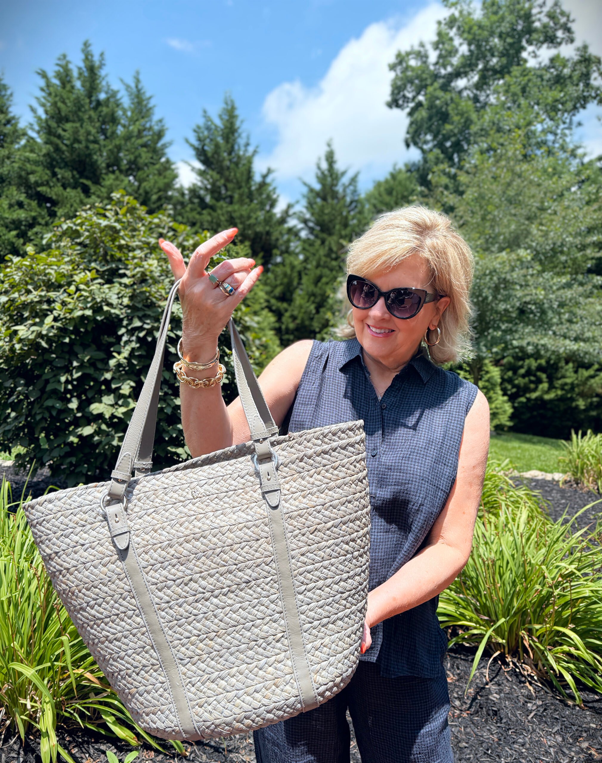 Woman carrying large rattan tote on beach with blue sky background