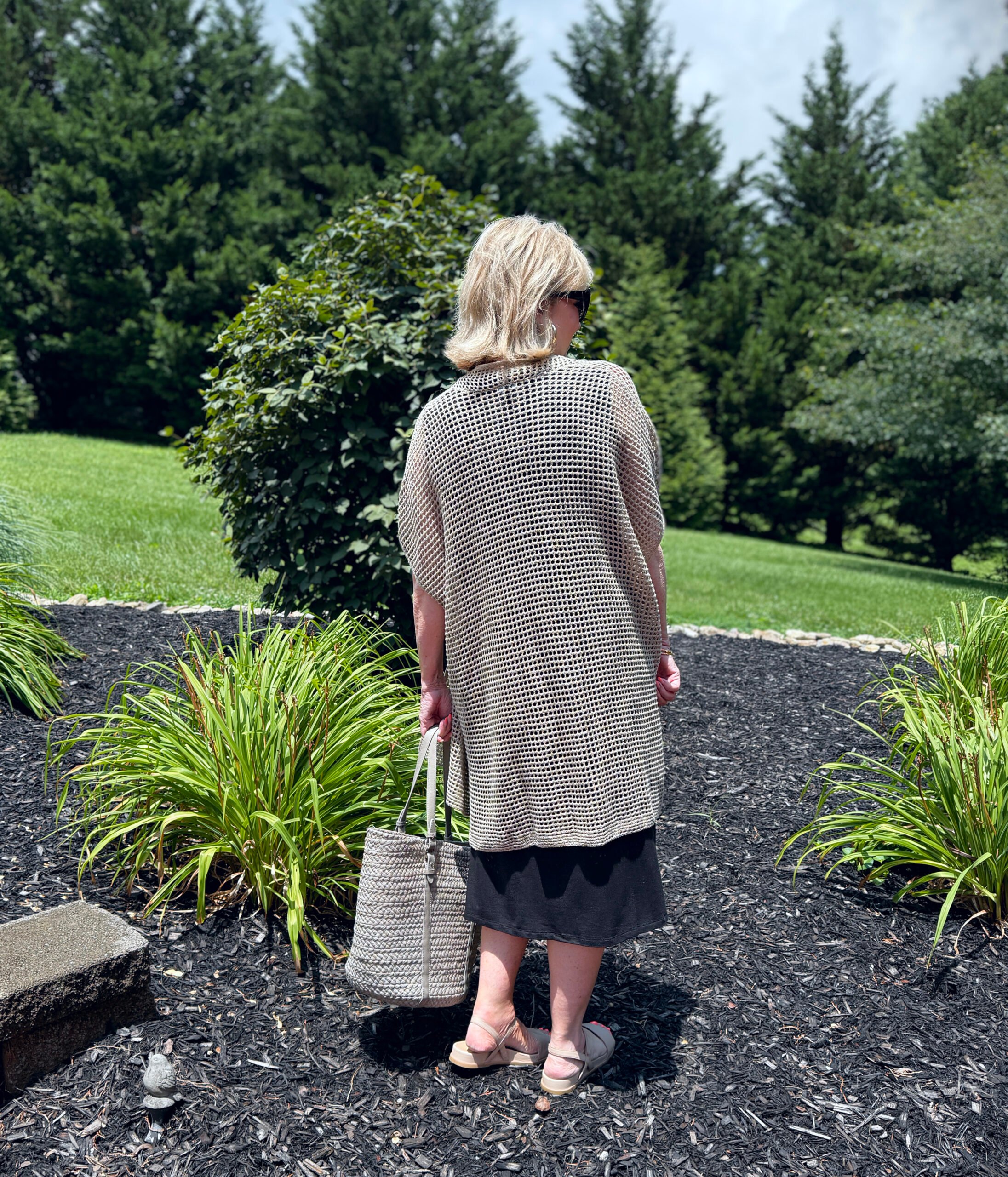 Tania showing the back of an Eileen Fisher black dress with a open weave cardigan from Nordstrom Rack