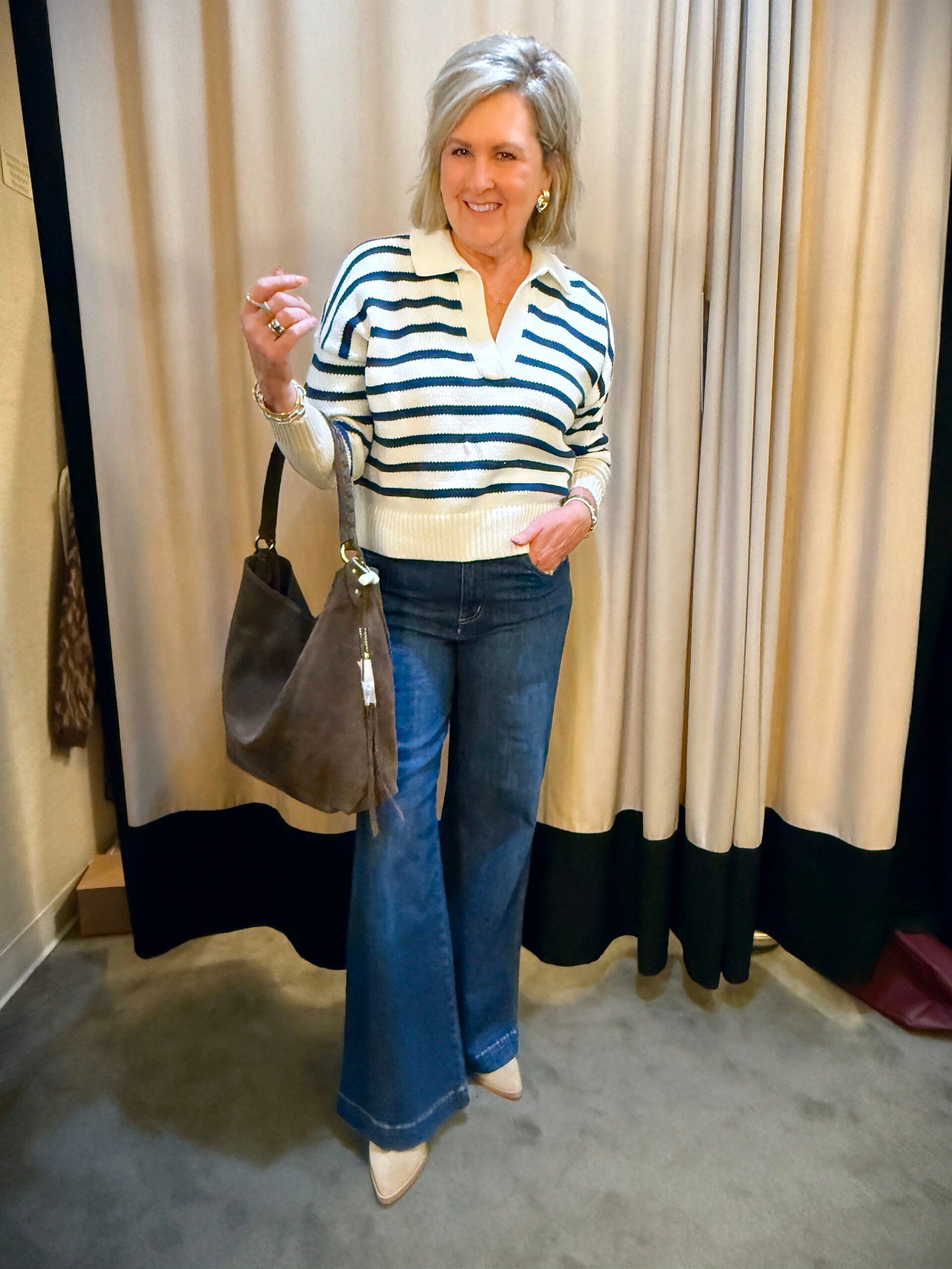Tania wearing a navy & white striped sweater with dark wash wide leg jeans